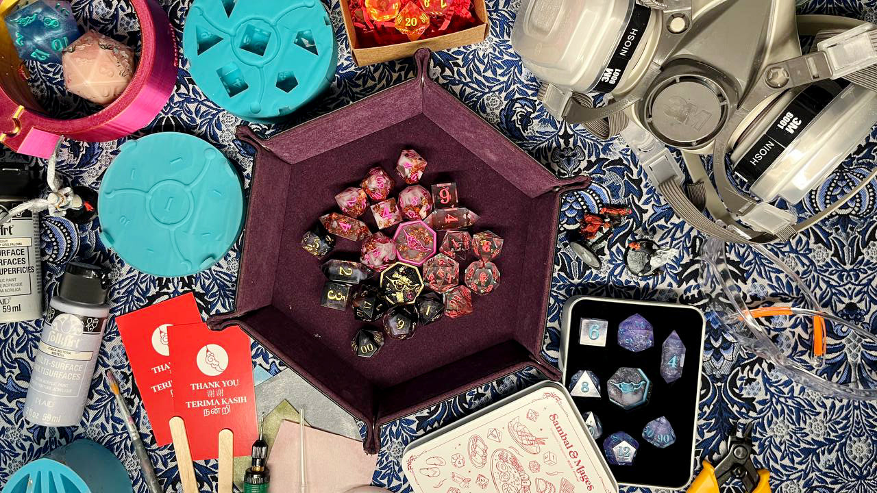 top down shot of dice making materials such as resin, paint, with a d&d dice tray in the centre with some d&d dice sets